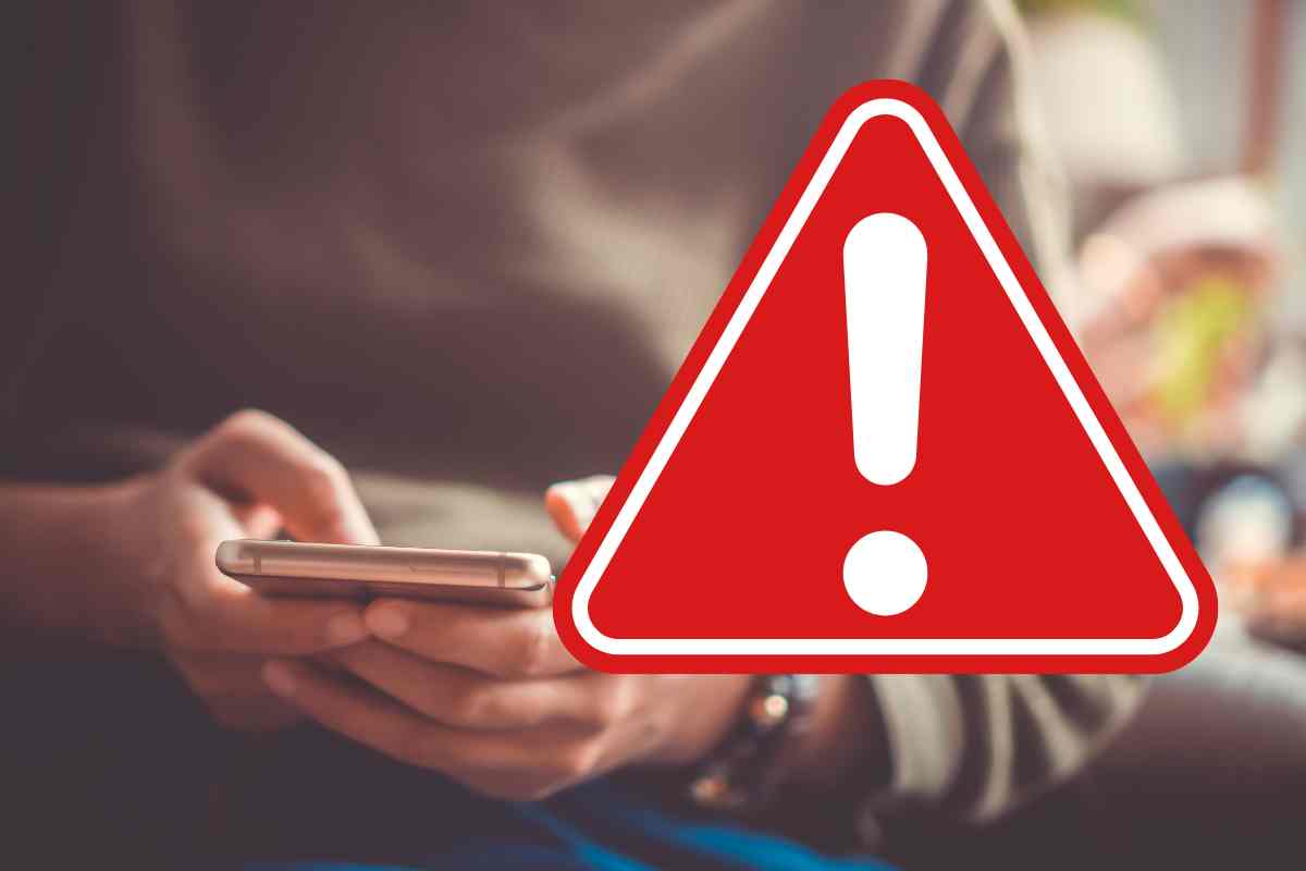 mani che usano uno smartphone e segnale di pericolo