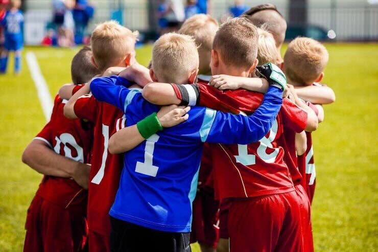 Bambini vestiti con completini da calcio si abbracciano 