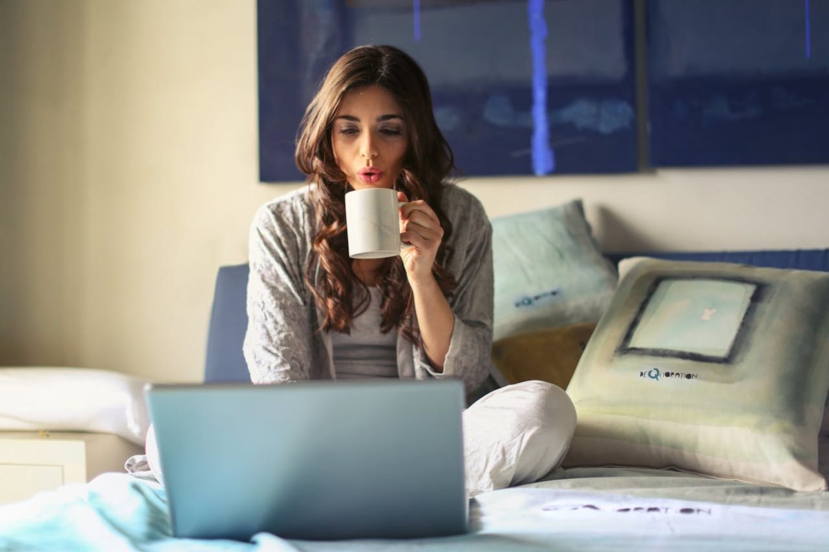 Ragazza al laptop con tazza in mano