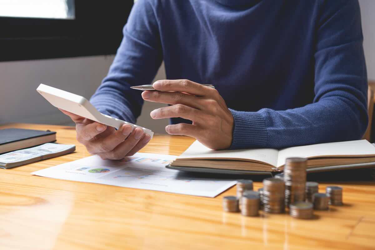 Uomo con calcolatrice, documenti, monete