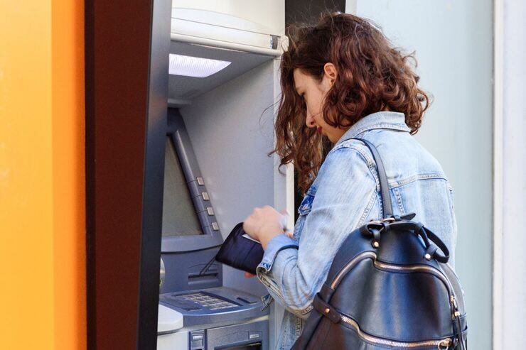 Donna allo sportello bancomat con portafoglio 