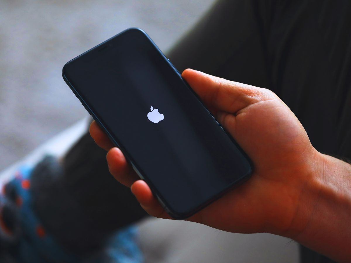 persona che tiene in mano un iphone con schermo nero e logo apple
