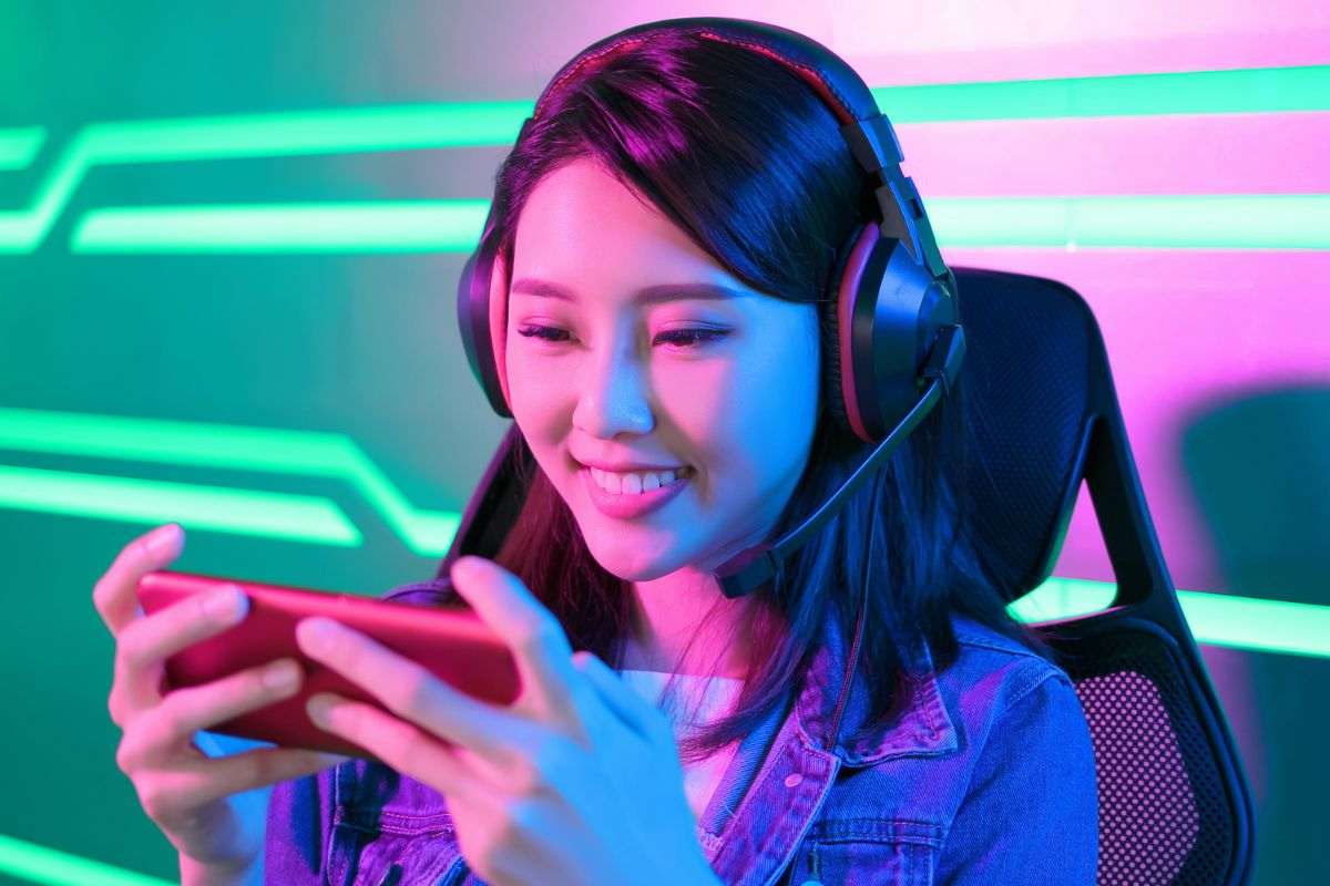 ragazza con cuffie gioca su smartphone in orizzontale