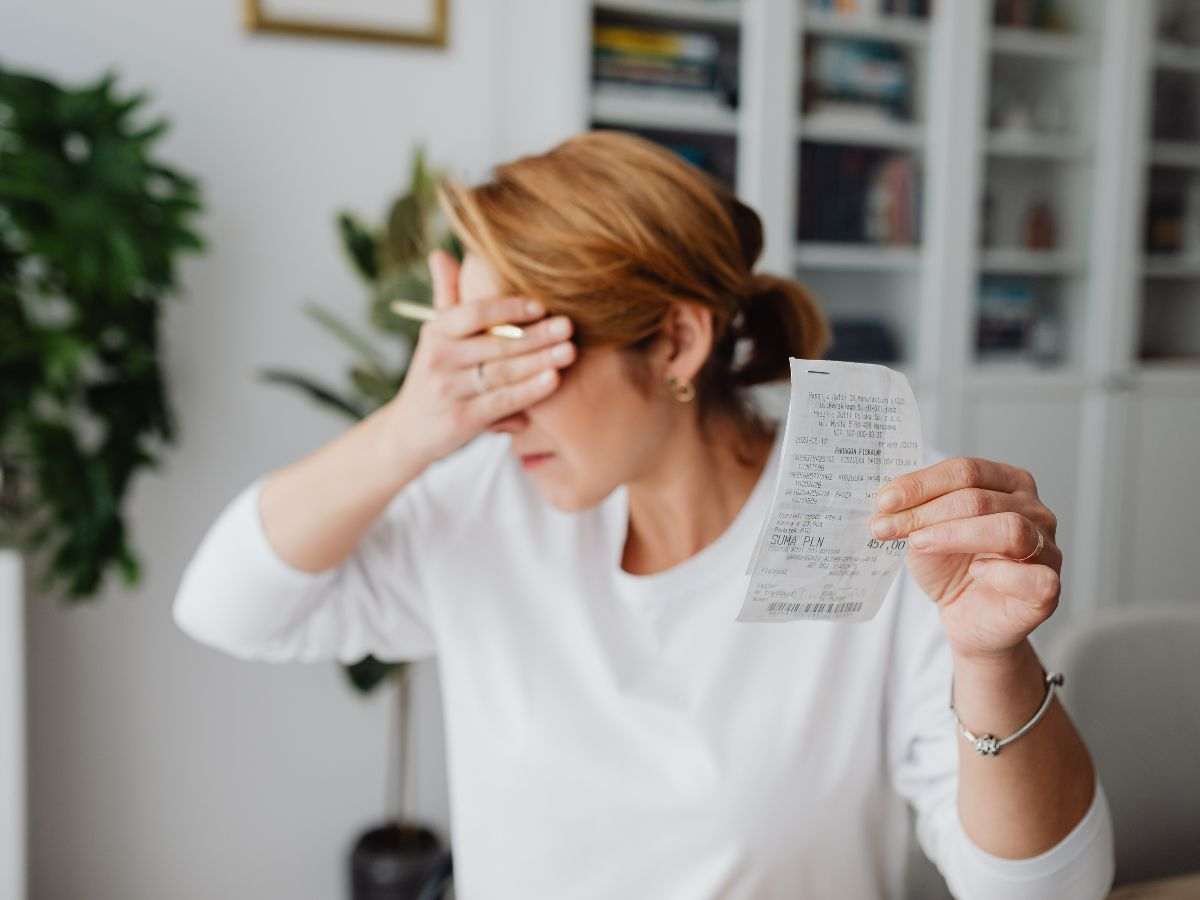 donna che ha in mano uno scontrino e si mette una mano sulla fronte