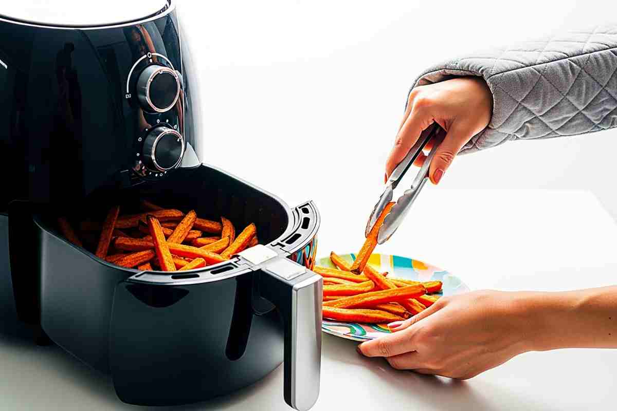 donna che tira fuori patatine da una friggitrice ad aria