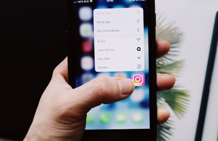 persona che clicca sull'icona dell'app di Instagram su smartphone