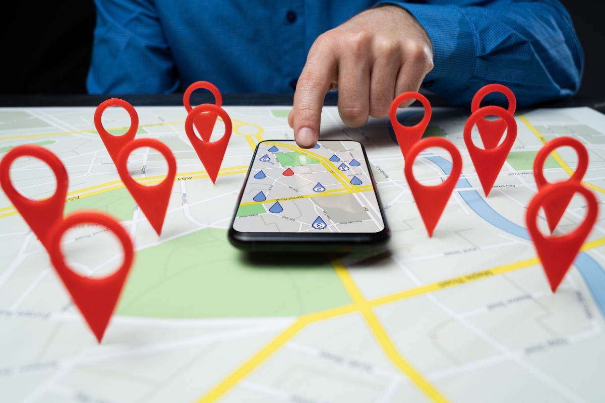 smartphone con google maps su mappa fisica con punti di riferimento in evidenza