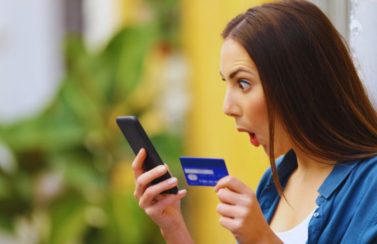 persona sorpresa con in mano un telefono e una carta di credito