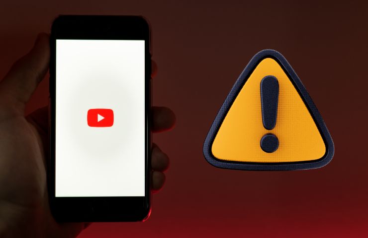 smartphone con logo youtube su sfondo rosso e segnale di pericolo accanto