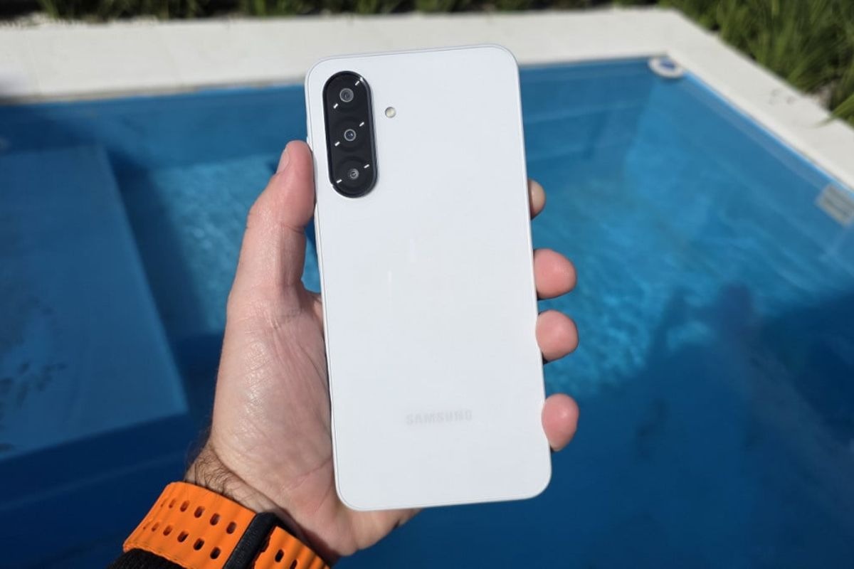 smartphone samsung tenuto n mano vicino piscina, colore bianco fotocamere