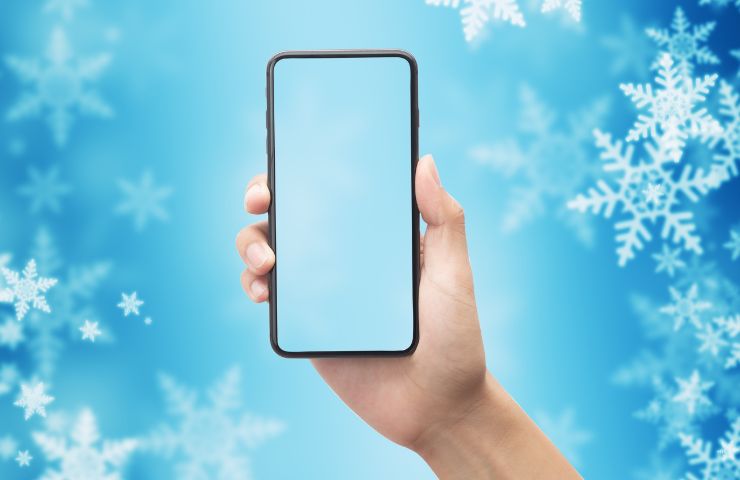 sfondo ghiacciato con mano che tiene uno smartphone