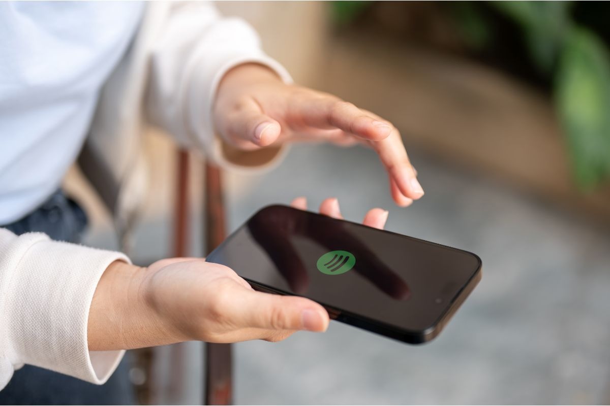 persona tiene in mano cellulare con logo spotify