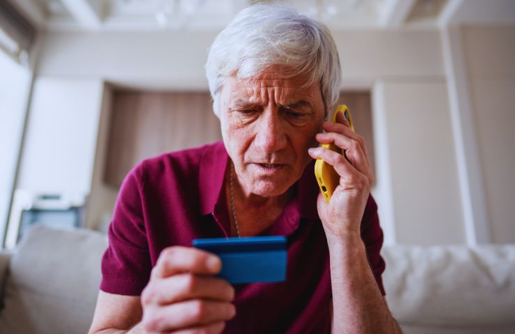 persona che telefona con carta di credito in mano preoccupata