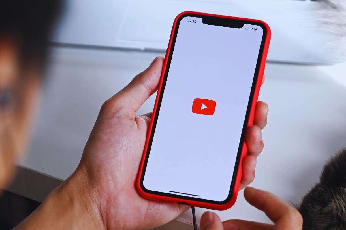 persona che tiene in mano uno smartphone con icona di YouTube