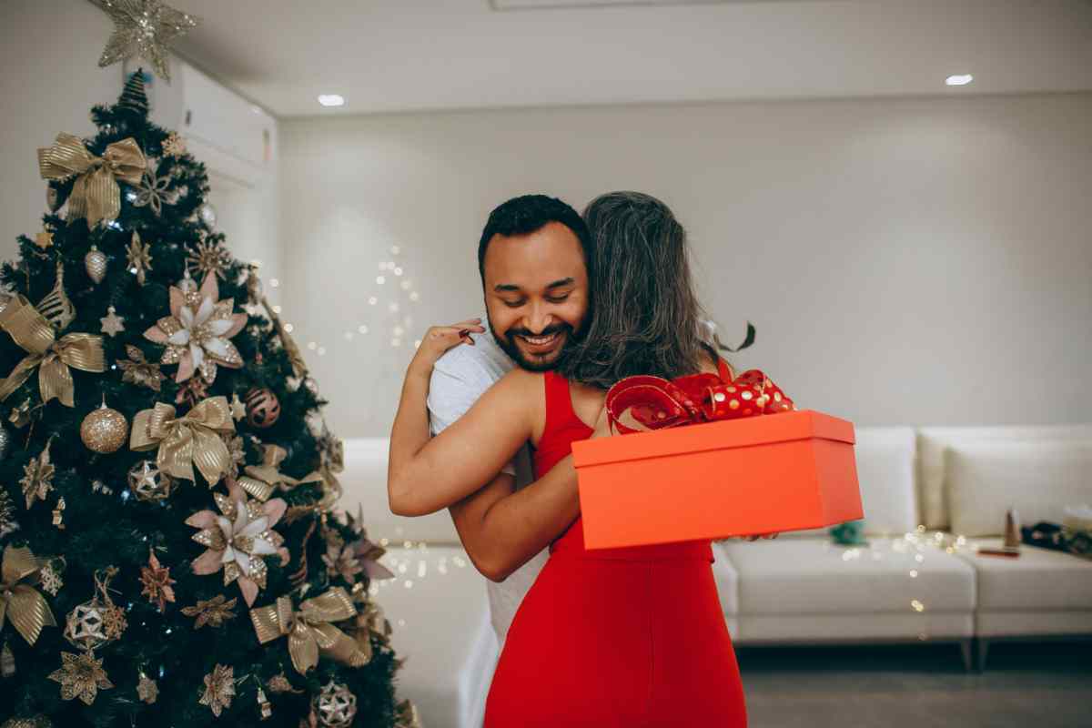 coppia si abbraccia con un regalo di Natale in mano