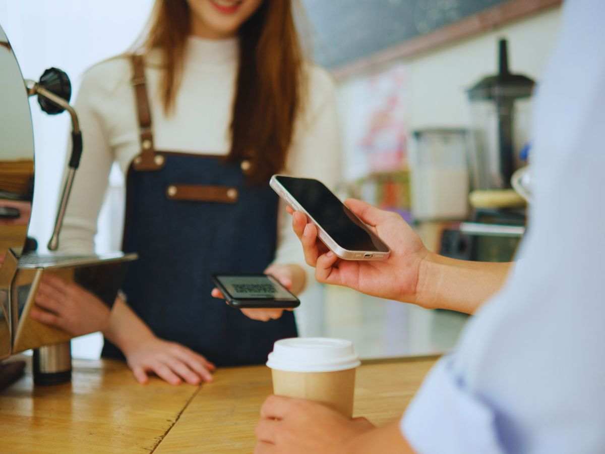 persona che paga il conto al bar con lo smartphone sul pos